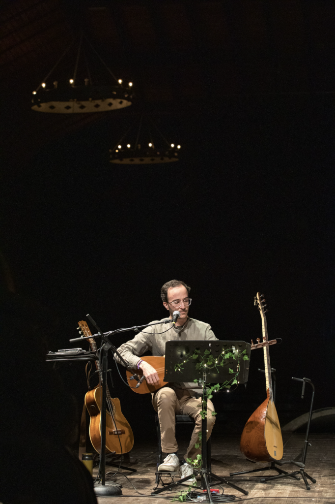 Bariş Ayhan jouant du saz, entouré d'un saz et d'une guitare